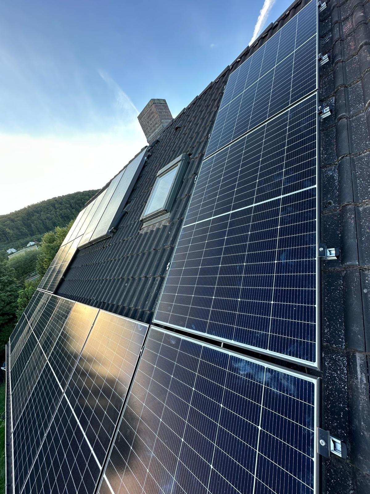 Detailaufnahme von Photovoltaik-Modulen auf einem Schrägdach mit Dachfenster
